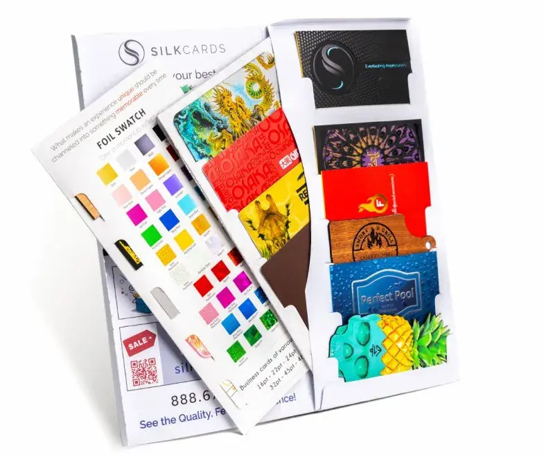 A display of various business cards and color swatches from SilkCards, showcasing different designs, textures, and finishes available for custom business cards.