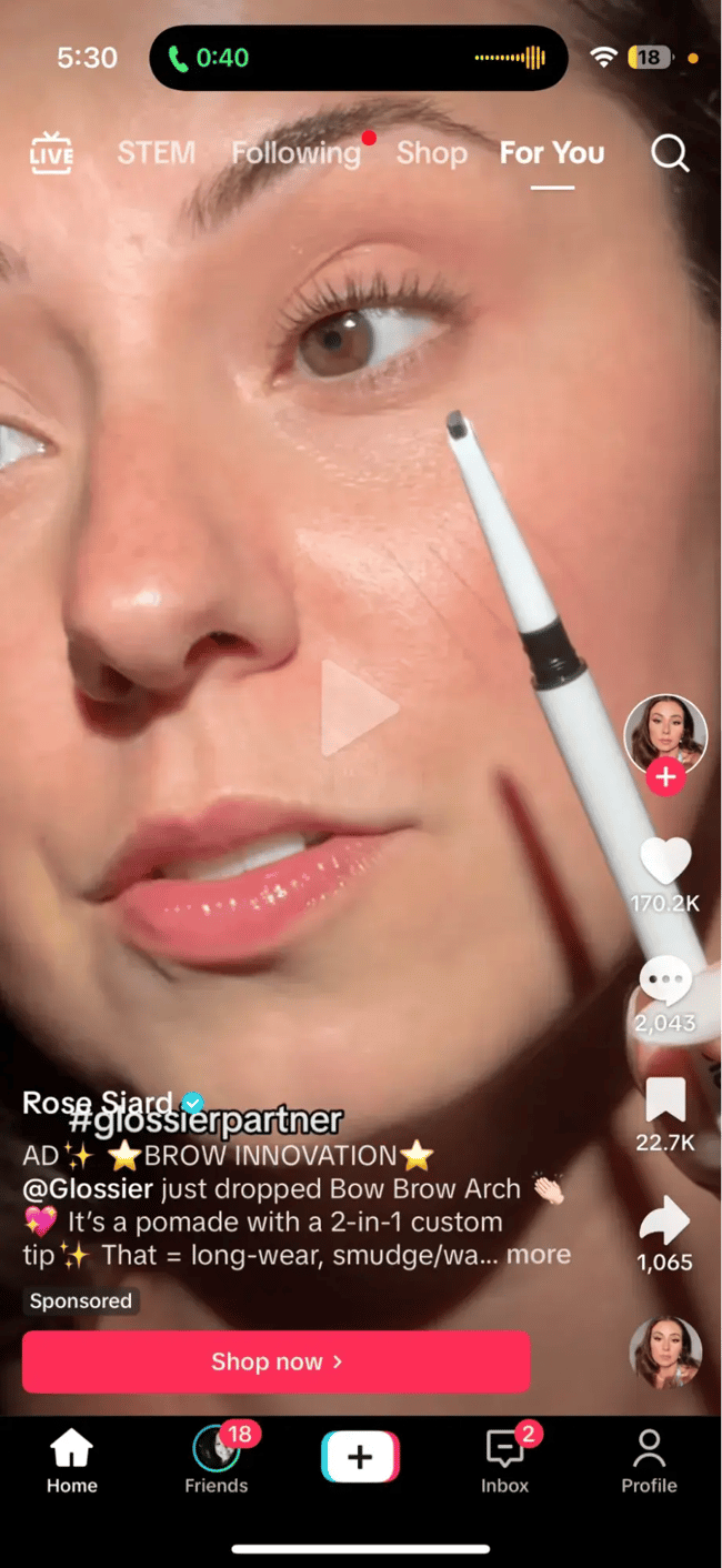 Screenshot showing an example of a Glossier TikTok ad with a blue call-to-action button